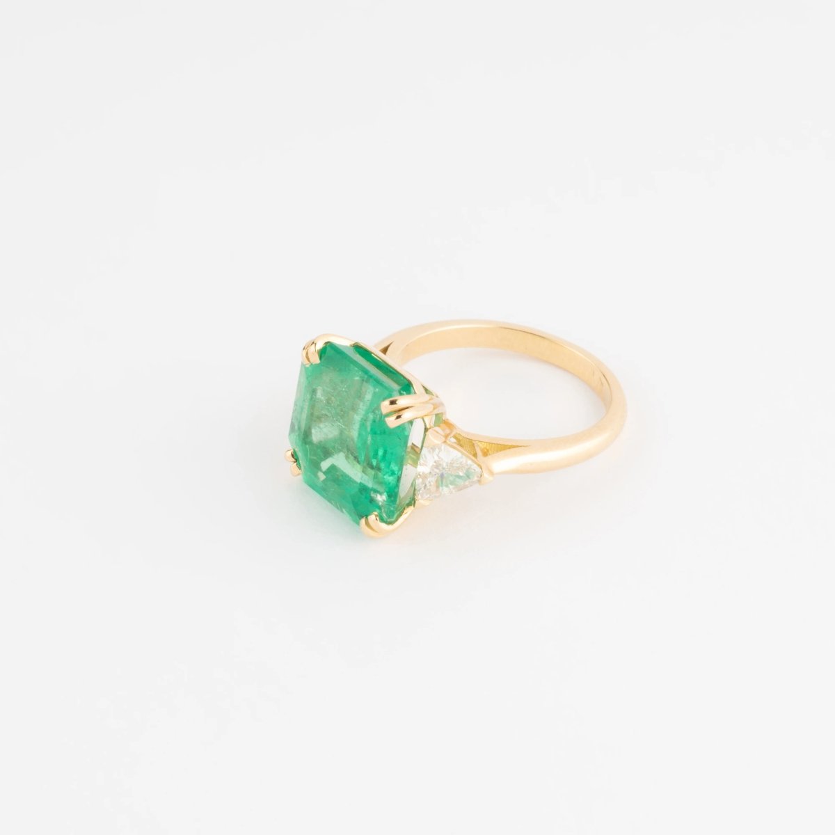 Bague en or jaune ornée d'une émeraude taille émeraude épaulé de diamants triangles - Castafiore